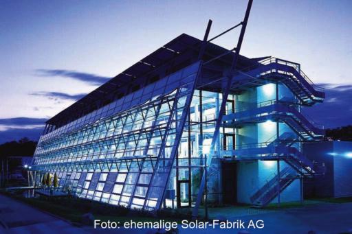 Eine bei Nacht im blauen Licht leuchtende Fassade eines Industriegebäudes: der ersten Solar-Fabrik in Freiburg.