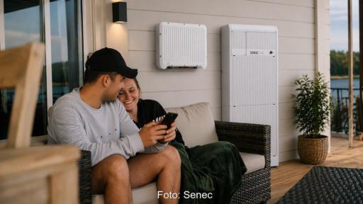 Ein Paar sitzt auf einen Sofa vor dem Haus neben dem Batteriespeicher Wall von Senec, den das Unternehmen auf der Intersolar/EES 2026 vorstellt.