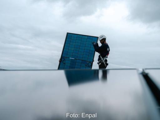 Monteur mit PV-Modul hinter einem PV-Dach.
