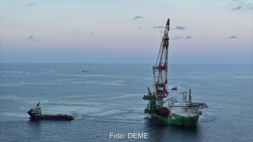 Ein Offshore-Installationsschiff mit großem Kran arbeitet auf ruhiger See an der Errichtung des Windparks Nordlicht I. Daneben liegt ein Versorgungsschiff; im Hintergrund ist die offene Nordsee zu sehen.