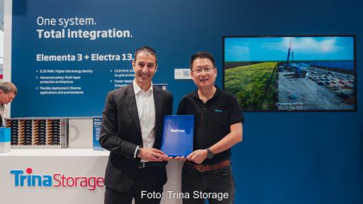 Zwei Männer halten eine Trina-Storage-Mappe vor einem Messestand.