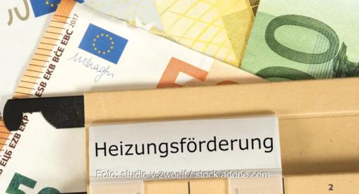 Mehrere Euro-Geldscheine - gelb, grün, braun - liegen unter einer beigen Akte mit der Aufschrift „Heizungsförderung“ und symbolisieren die staatliche Förderung für den Heizungstausch.