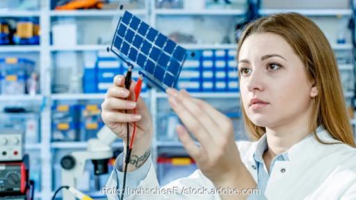 Frau in Laborkittel hält Solarzellen in die Luft, in aktiven, nur wenige Nanometer dünnen Schichten von neuen Solarzellen gelten die Gesetze der Quantenmechanik.