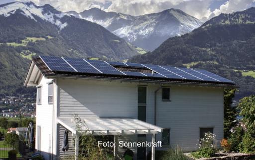 Ein Haus mit Solaranlage vor Bergkulisse, die Photovoltaik-Förderung in Österreich steht in der Kritik.