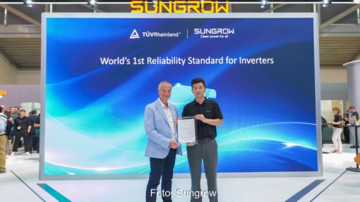 Zwei Vertreter von TÜV Rheinland und Sungrow präsentieren auf einem Messestand ein Zertifikat für neue Zuverlässigkeitsstandards von PV-Wechselrichtern. Im Hintergrund ist eine große Bildschirmwand mit den Logos beider Unternehmen zu sehen.