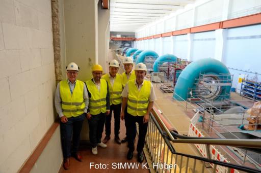 Fünf Personen in Sicherheitswesten und Helmen in Maschinenhalle eines Pumpspeicherkraftwerks.