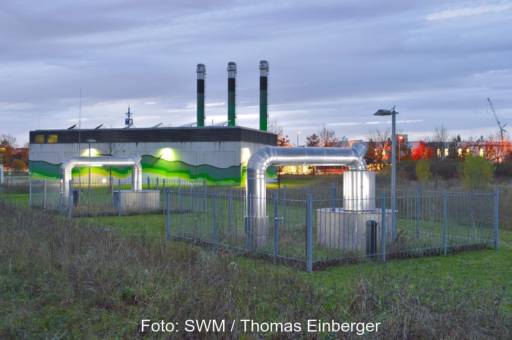 Beleuchtetes Heizkraftwerk nach Sonnenuntergang mit Rohren, die in den Untergrund führen.