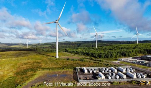 Ein Windpark hinter Batteriespeicher-Containern, die Windpark-Software Unified Wind Farm Scada führt Windenergieanlagen, Umspannwerke und Speicher auf einer zentralen Betriebsplattform zusammen.