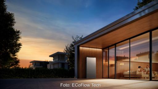 EcoFlow OCEAN 2 Batteriespeicher an einer Hauswand eines moderner Flachbau-Wohngebäudes in der Abenddämmerung mit Familie im Wohnraum.