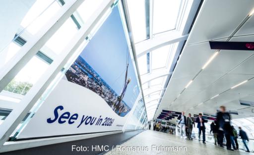 Besucherinnen und Besucher gehen durch einen hellen Verbindungsgang der Hamburg Messe. Auf einer großen Wandgrafik steht „See you in 2026!“.