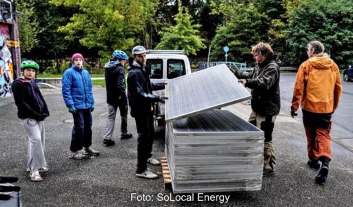 Ein Stapel gebauchte Solarmodule und Menschen, die diese für Balkonkraftwerke umrüsten.