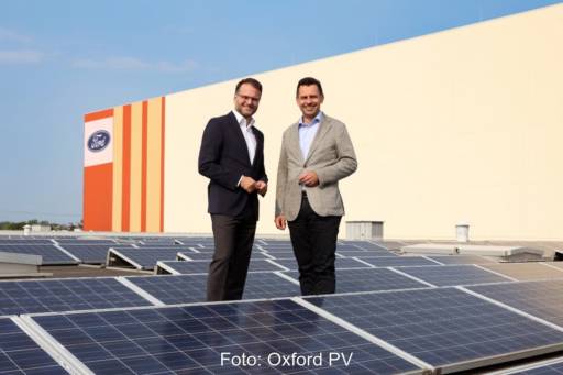 Zwei Männer auf einem Industriedach zwischen PV-Modulen.