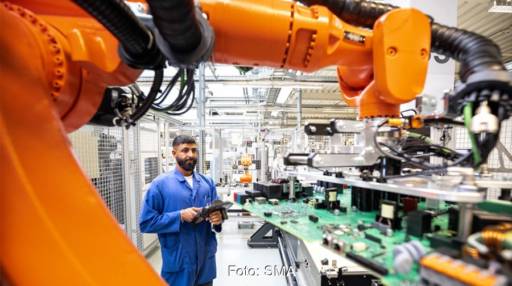 Im Bild ein Arbeiter unter einem Roboterarm in der neuen SMA Elektronikfertigung.