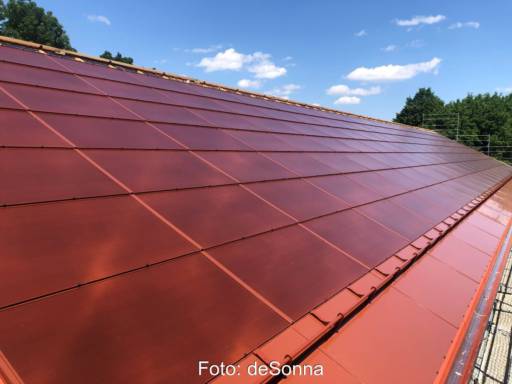 Eine dachintegrierte PV-Anlage mit roten Modulen.