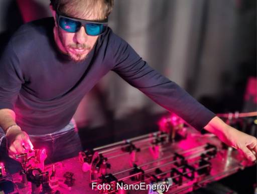 Ein Forscher mit Schutzbrille arbeitet bei rotem Licht an einer Apparatur.