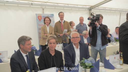 Drei Menschen (Habeck, Neubaur, Vogel) sitzen am Tisch in einem Zelt, im Hintergrund stehen zwei Menschen an der Zeltwand - Einweihung von Wald-Windpark