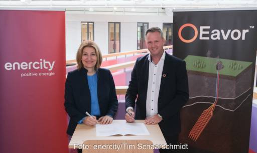 Eine Frau und ein Mann halten Kugelschreiber über einem Papier und schauen in die Kamera - Unterzeichnung Wärmeliefervertrag von Eavor und Enercity.