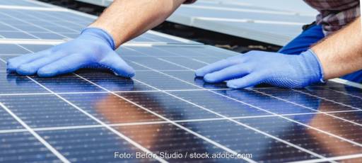Zwei Hande mit Schutzhandschuhen bei der Handhabung von Solarmodulen.