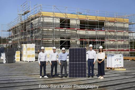 Sechs Personen un ein großes Solarmodul auf einer Baustelle.