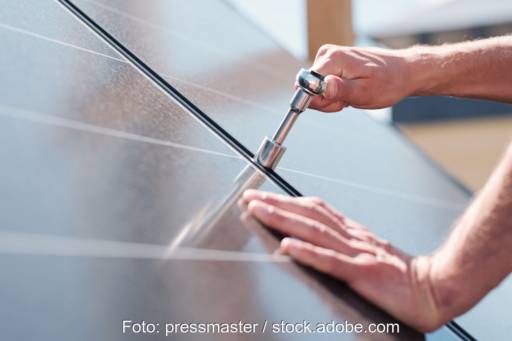 Symbolbild für Photovoltaik-Umsatzsteuer: Handwerker schraubt Modulklemmen einer Photovoltaikanlage fest.