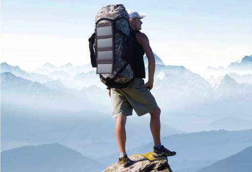 Im Bild ein Mann auf einer Bergspitze, der ein faltbares Photovoltaik-Panel auf dem Rucksack befestigt hat. Foto: Pearl GmbH