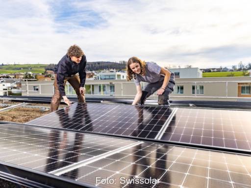 Ein junger Mann und eine junge Frau auf einem Dach halten ein Solar-Modul - die Schweiz führt neue Solarlehren ein.