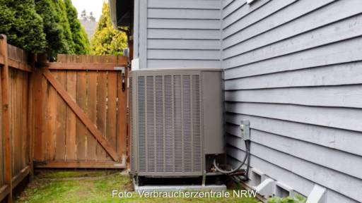 Luft-Wärmepumpe mit wenig Abstand: Das Bild zeigt am linken Rand einen Gartenzaun, dicht daneben eine Wärmepumpe an der Hauswand.
