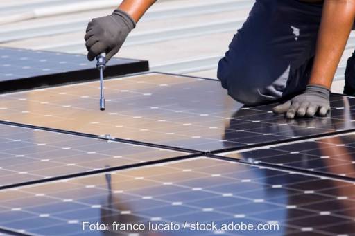 Flachdach mit PV-Modulen, die ein Handwerker im Begriff ist zu montieren.