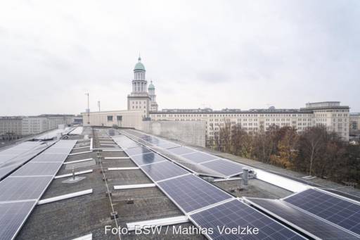 PV-Module auf einem Flachdach. Im Hintergrund Kirchtürme von Berlin.