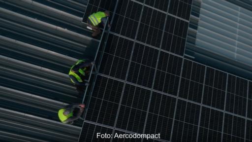 Drei Männer in gelben Warnwesten montieren eine PV-Anlage.