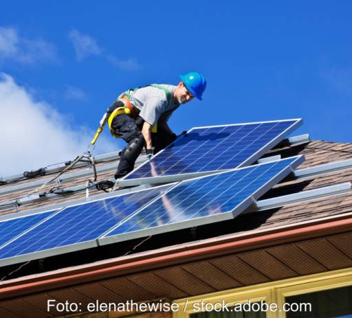 Ein Installateur verlegt Solarmodule auf dem Dach.