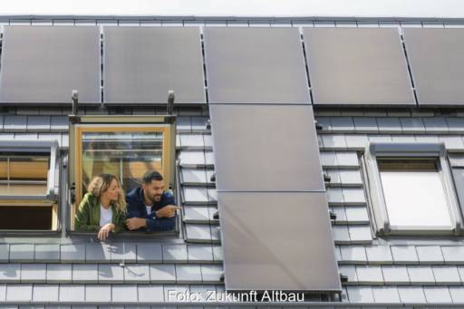 Ein junges Paar schaut aus einem Dachfebster auf installierte PV-Module.