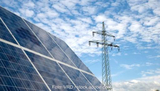 Im Bild Photovoltaik-Module und ein Strommast als Symbol für die Diskussion um die Differenzverträge (Contracts for Difference) in der EU.