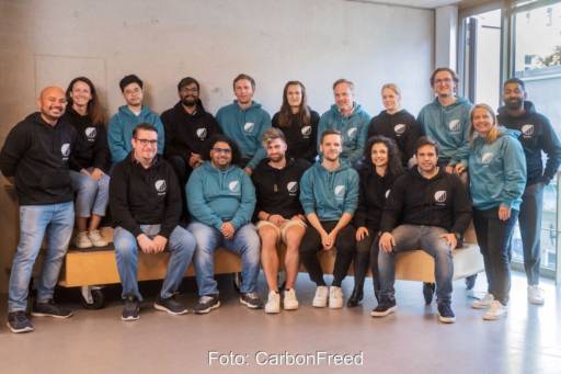 Mitarbeiter in lässigen Pullis mit Carbonfreed-CI posieren für ein Gruppenbild.