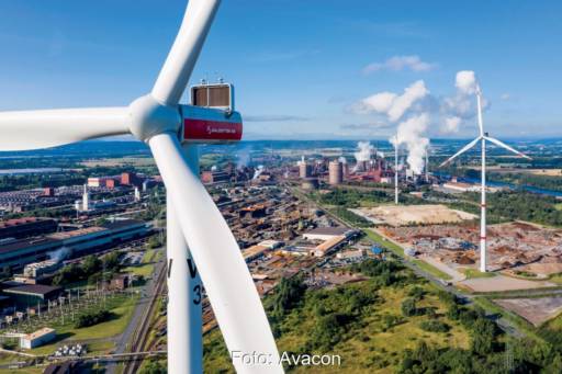 Im Vordergrund eine Windkraftanlage, im Hintergrund ein Industriegebiet - eine Option für die direkte Lieferung von Windstrom an die Industrie