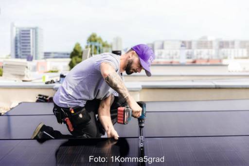 Ein Monteur installiert ein PV-Modul auf einem Hochhausdach.