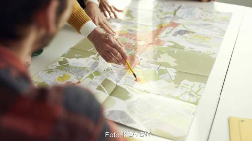 Das Bild zeigt Menschen rund um eine Karte, Symbol für kommunale Wärmeplanung, bei der man u.a. Erdwärme-Sonden und Wärmepumpen nutzen kann.