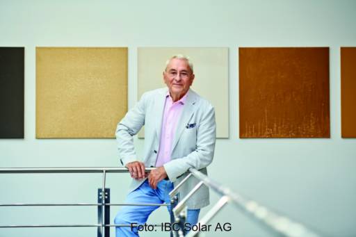 Der 83-jährige Udo Möhrstedt von IBC mit den Händen auf einem Geländer. Im Hintergrund eine Wand mit farbigen Flächen.