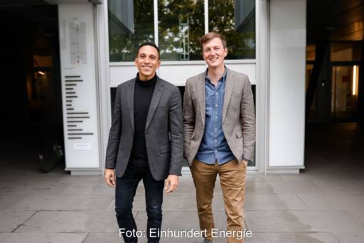 Die Gründer der Einhundert Energie, Ernesto Garnier und Markus Reinhold stehen lächelnd vor einem Haus.